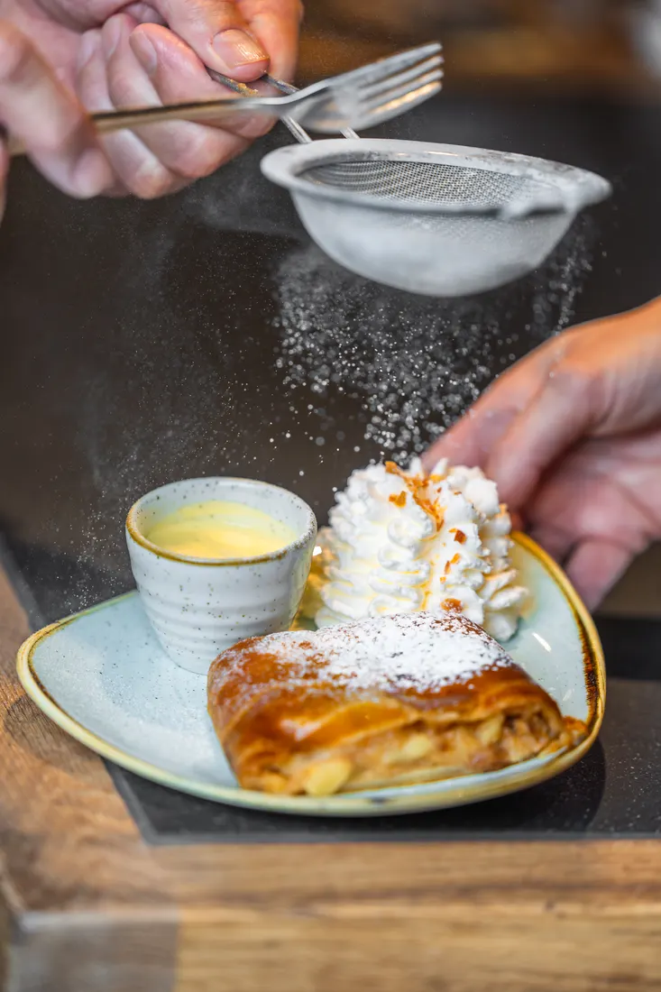 Poedersuiker wordt over apfelstrudel gezeefd